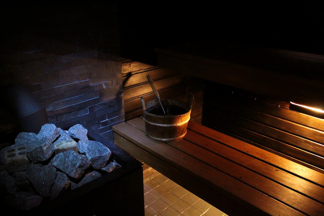 Traditional sauna with rocks, bucket, and wooden interior