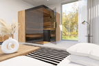 Thermasol Aalto indoor sauna with tinted glass and light oak slat panels, seen from a bed in a bright bedroom